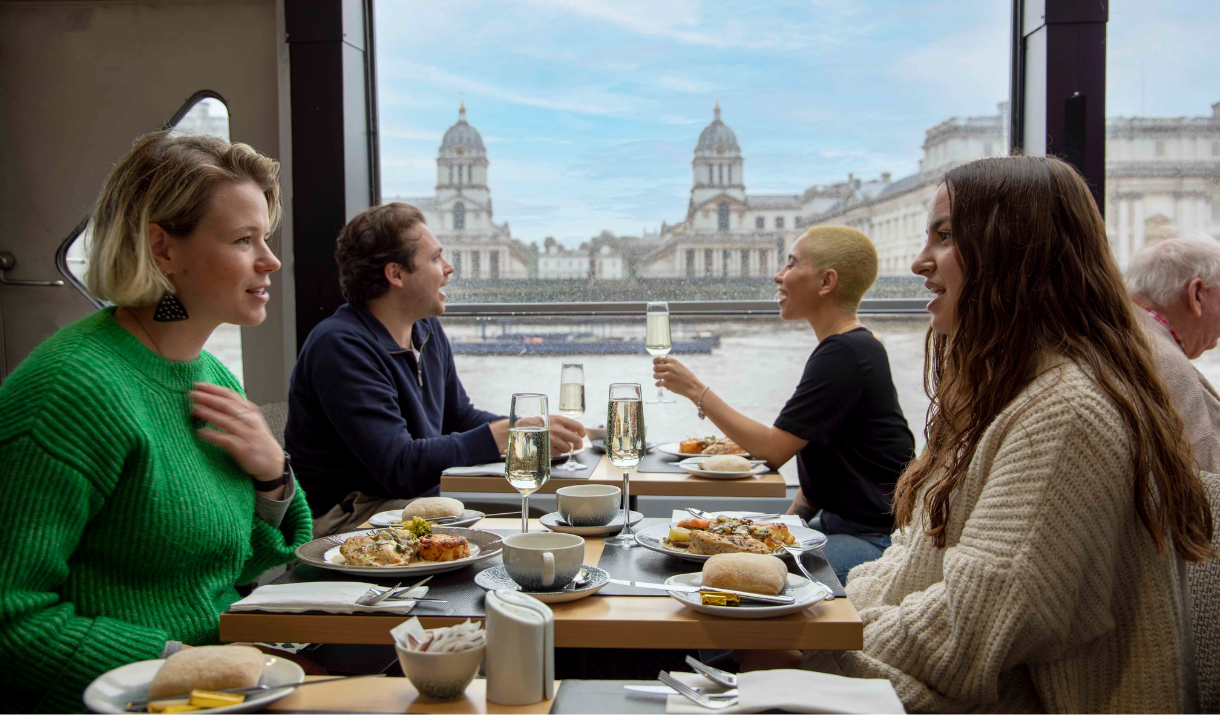 People enjoy food and drink on board City Cruises in front of the Old Royal Naval College, Greenwich
